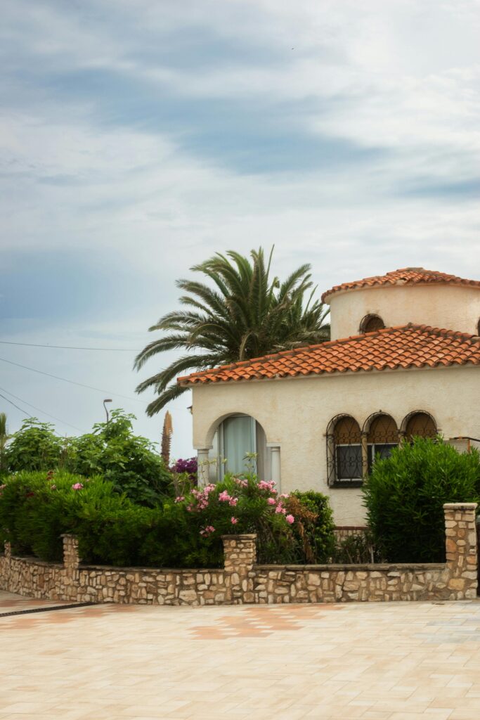 A beautiful Mediterranean-style villa with a garden of vibrant greenery and flowers.